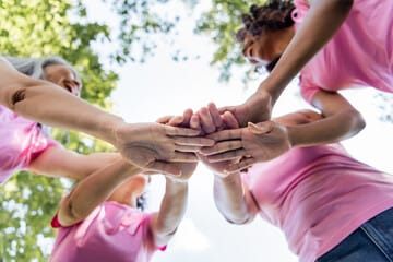 Un groupe de femmes empilent leurs mains pour symboliser le travail d’équipe et le soutien