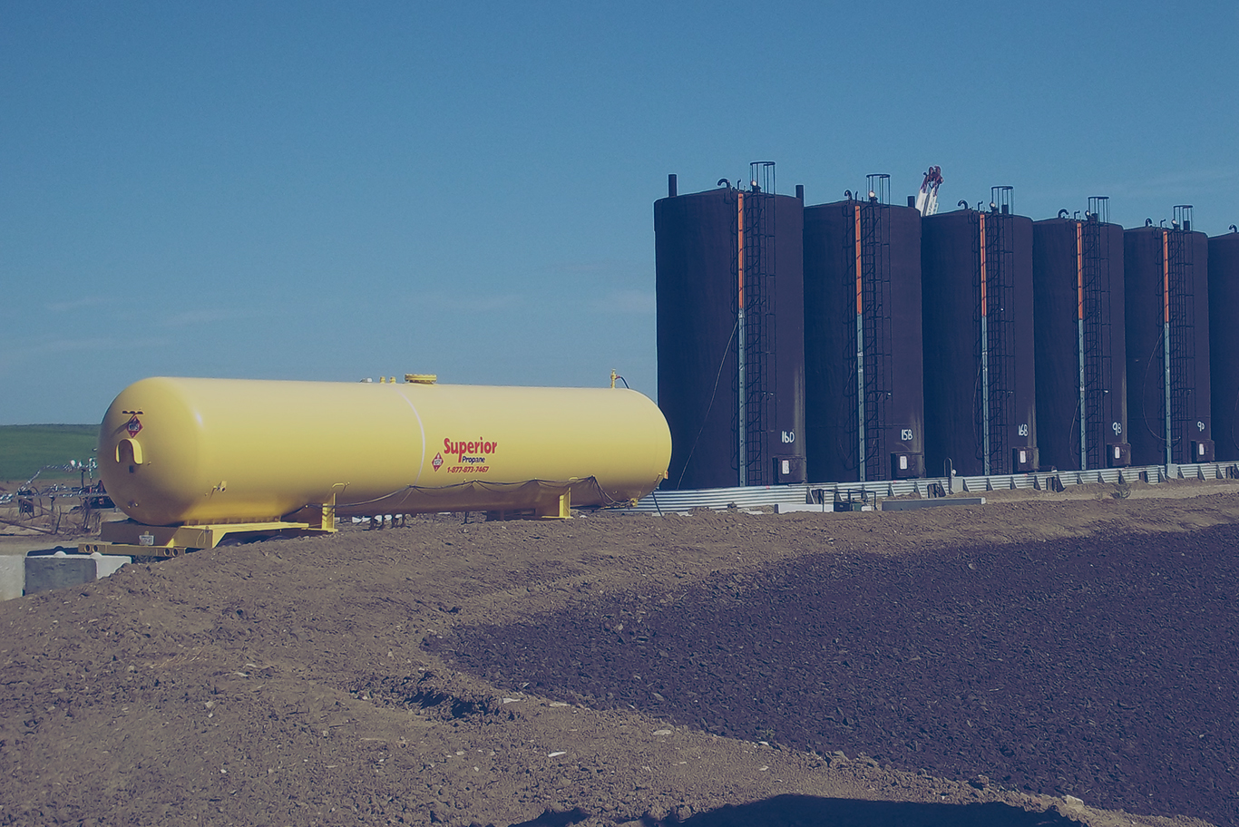 Un grand réservoir de propane supérieur jaune à côté de plusieurs silos.