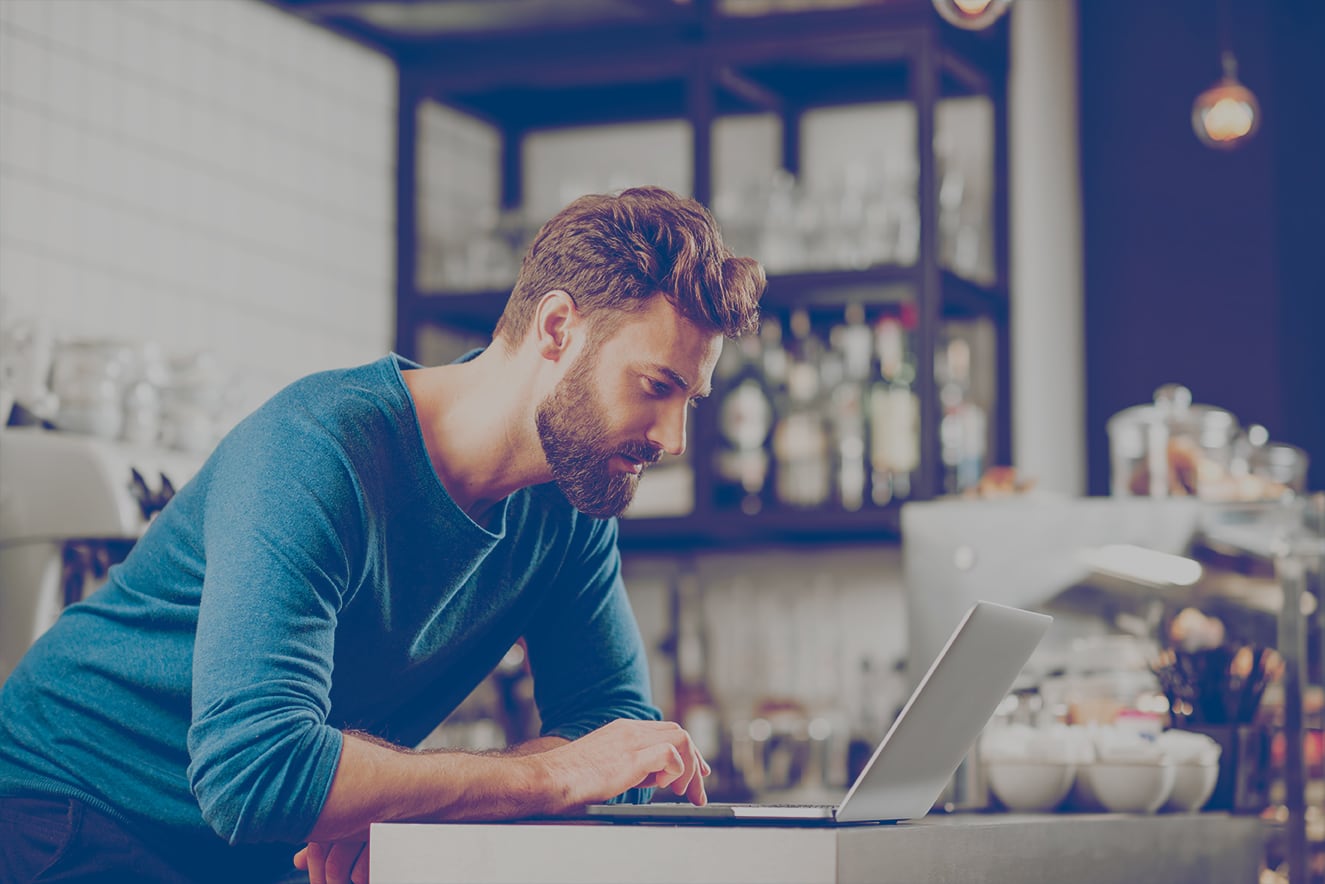 Homme travaillant sur un ordinateur portatif, au comptoir d’un café