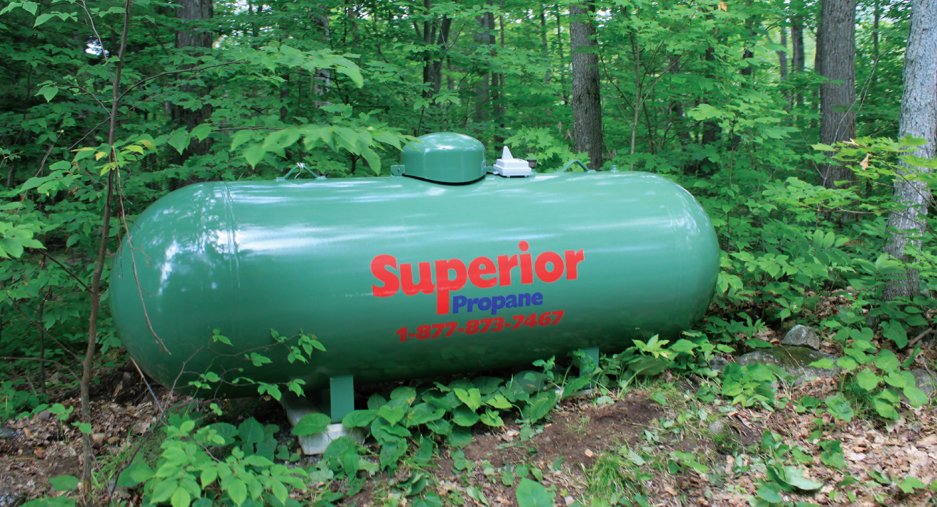 Réservoir vert de Supérieur Propane dans un secteur boisé