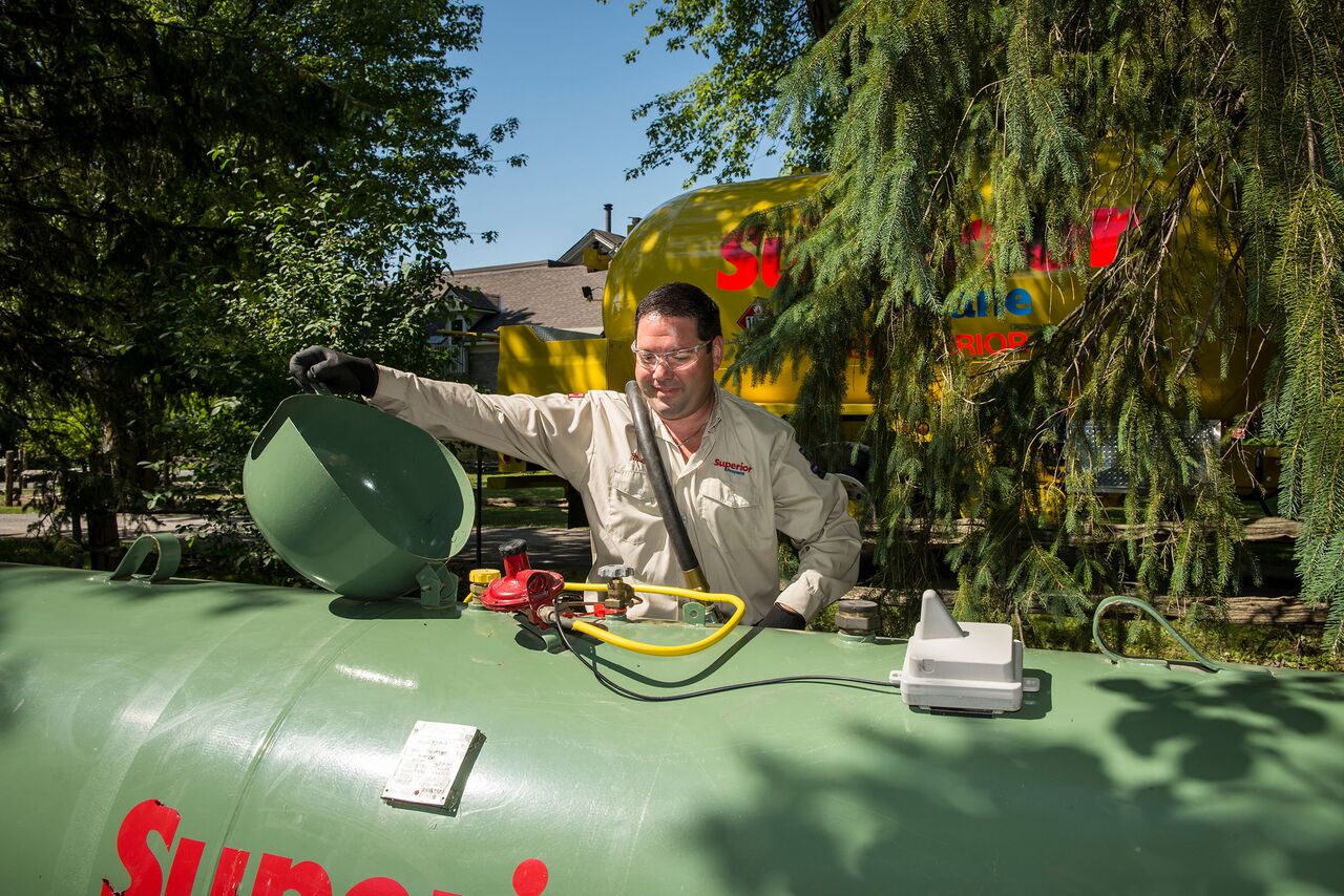 Employé de Supérieur Propane ouvrant un réservoir de propane de couleur verte, pour le remplir.