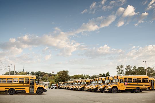 Grand parc d’autobus scolaires jaunes garés dans un parc de stationnement.
