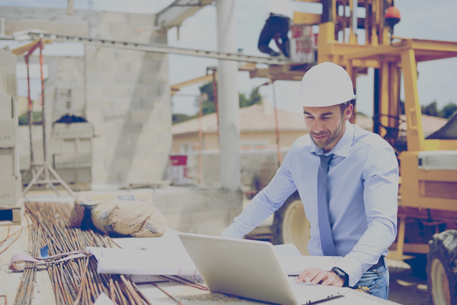 Un ingénieur regarde des plans et un ordinateur portable sur un chantier de construction.
