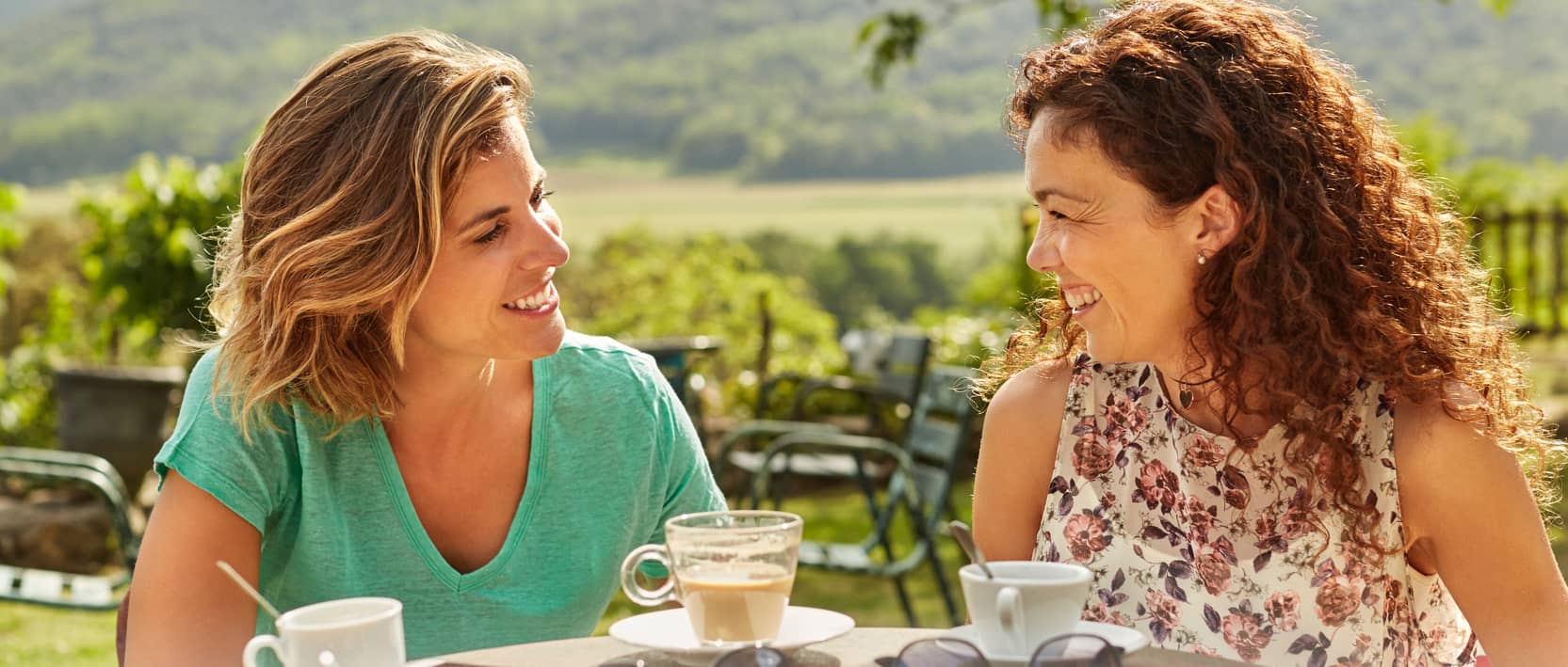 Deux amies buvant un café sur une terrasse. Cliquez pour découvrir notre Programme recommandez un ami.