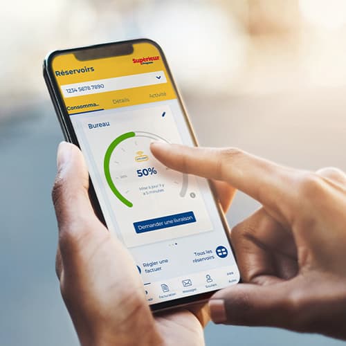 Mains tenant un téléphone portable avec l'application monSUPÉRIEUR ouverte pour vérifier les niveaux des réservoirs de propane