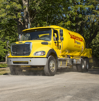Un camion jaune de Supérieur Propane se déplaçant sur un chemin de terre