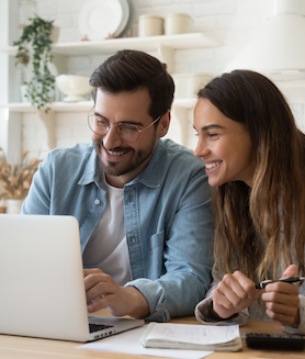 Un jeune couple heureux utilisant un ordinateur portable pour planifier son budget mensuel