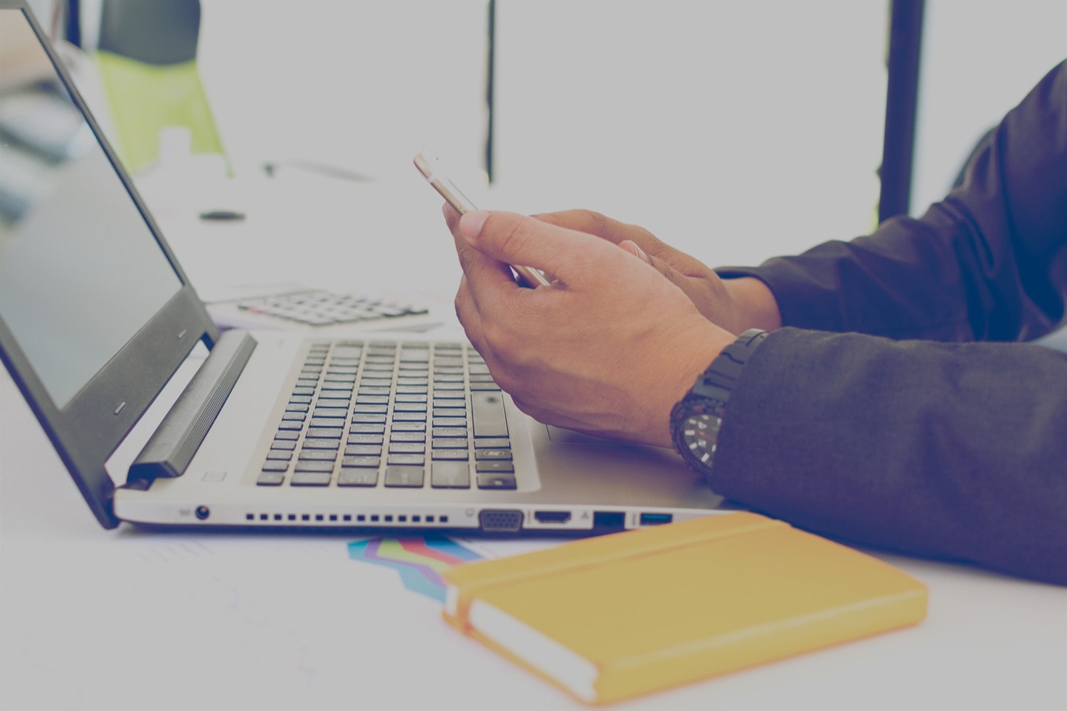 Personne travaillant sur un ordinateur portatif et utilisant une téléphone (cellulaire)