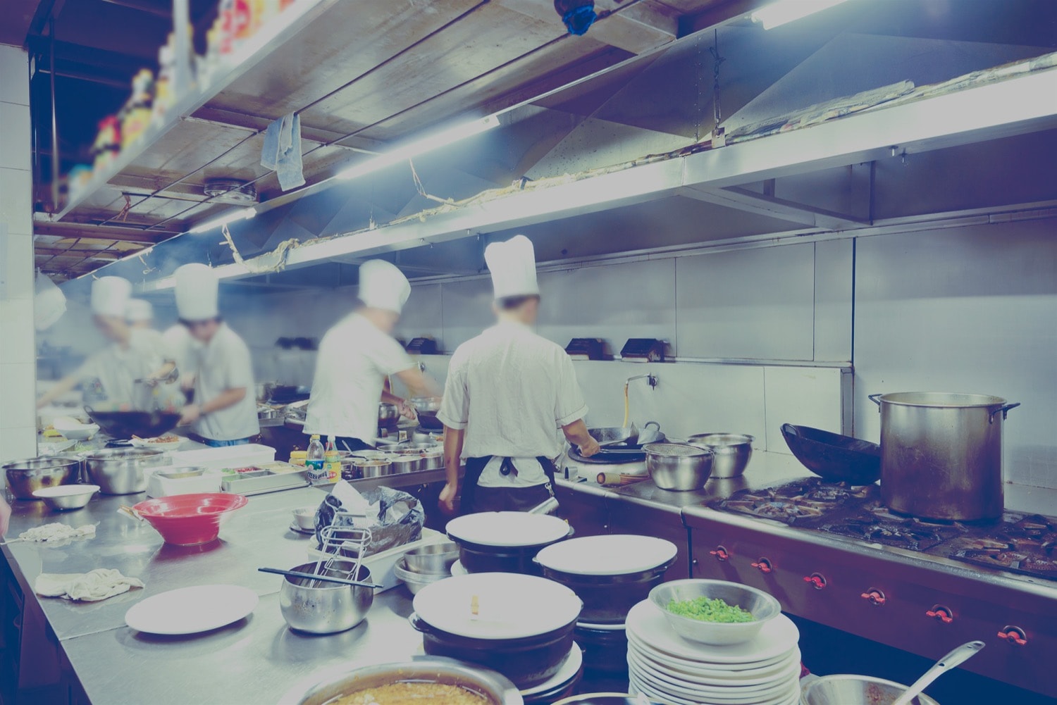Plusieurs cuisiniers travaillent dans la cuisine d’un grand restaurant avec des cuisinières et de fours alimentés au propane.