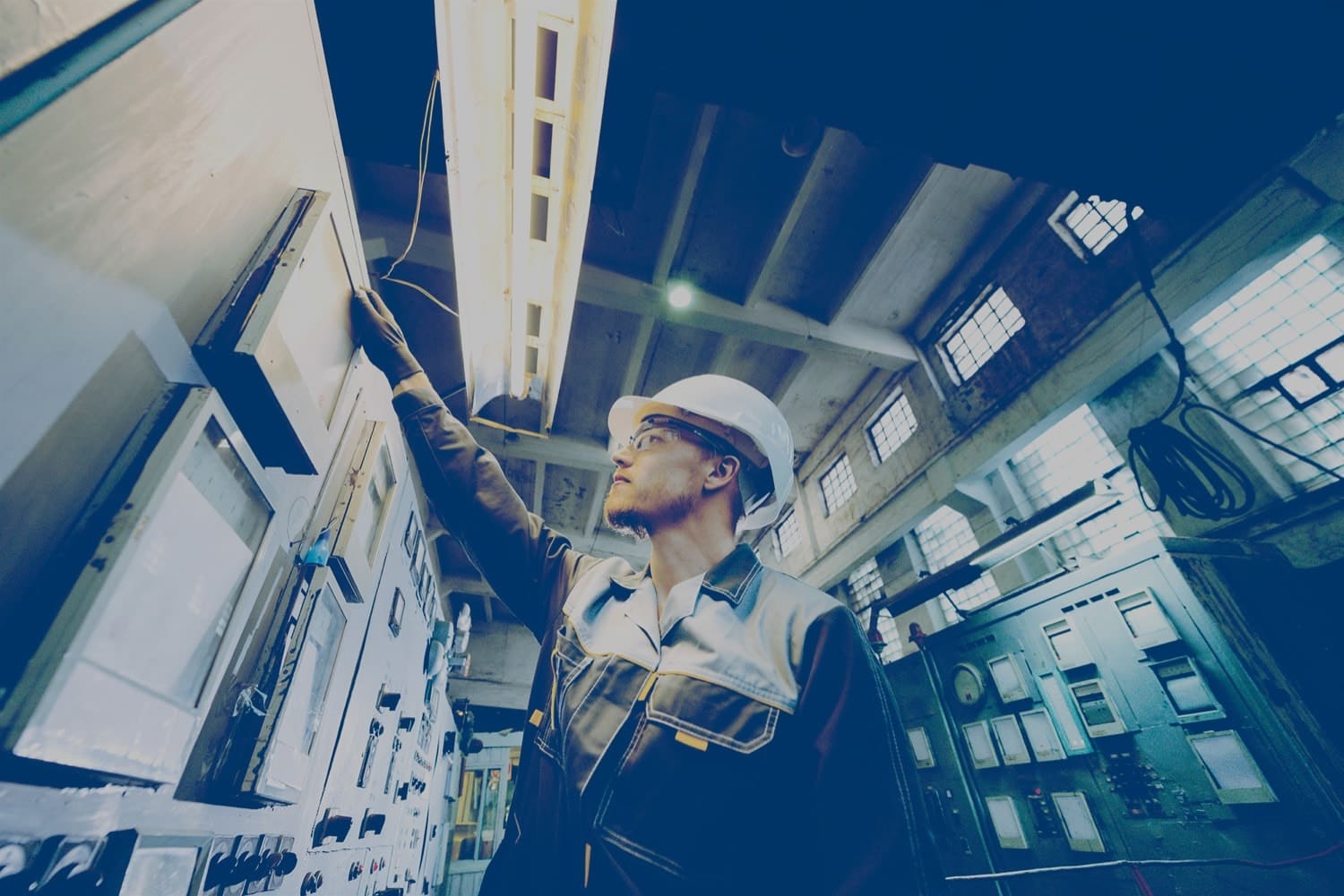 Un travailleur masculin dans un casque blanc contrôle de l'équipement électronique dans un grand bâtiment