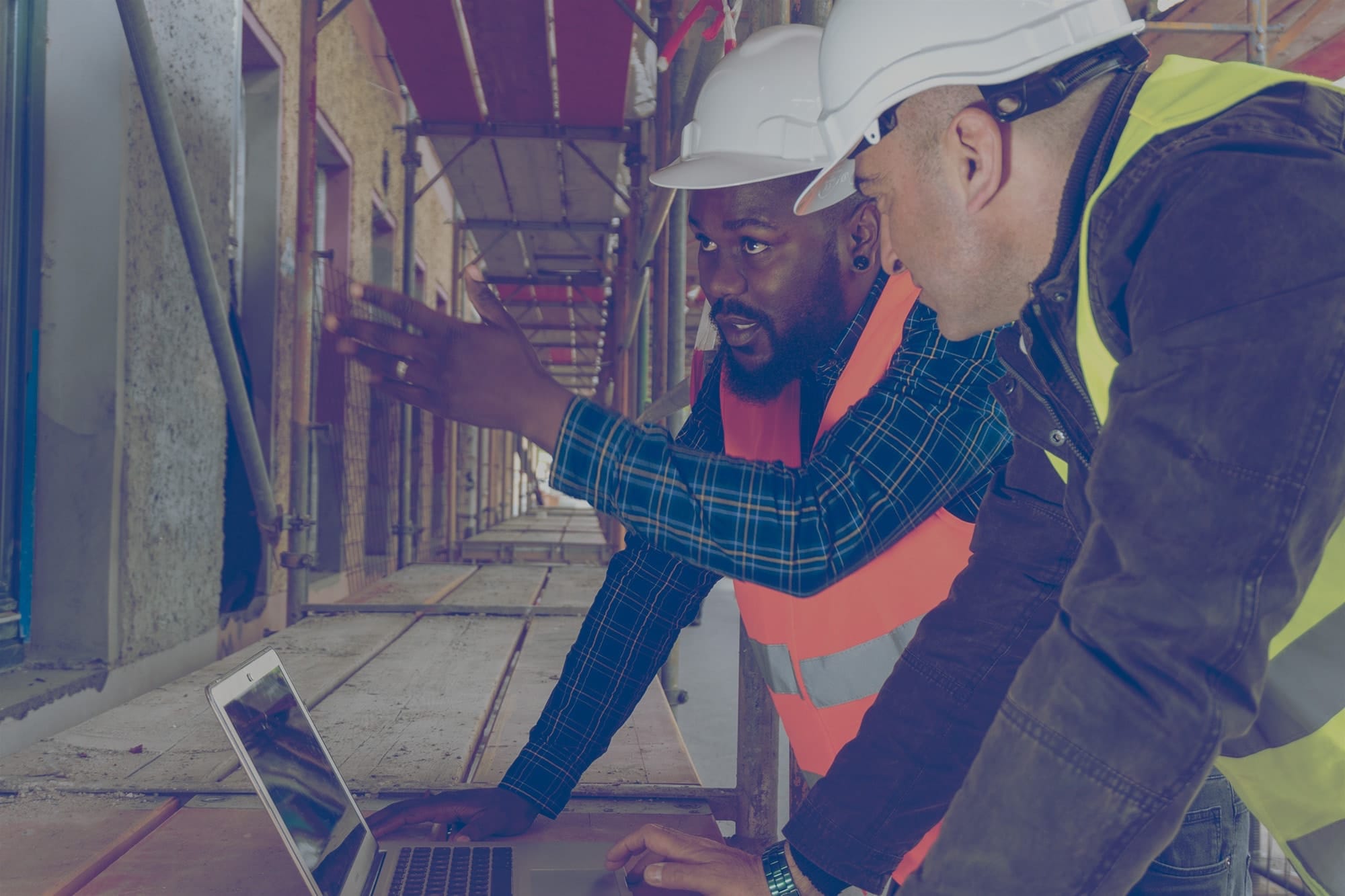 Deux entrepreneurs partenaires de Supérieur regardent l’écran d’un ordinateur portable sur un chantier de construction.