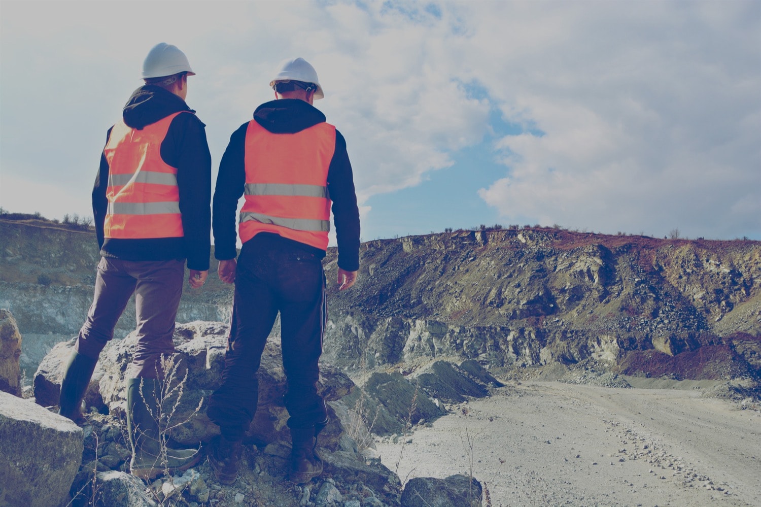Deux travailleurs de la construction regardent une vaste mine à ciel ouvert.