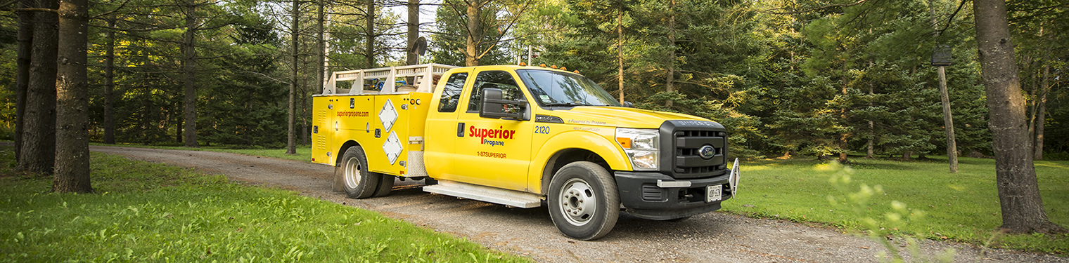 Un camion de service de Supérieur Propane en mouvement sur un chemin de terre.