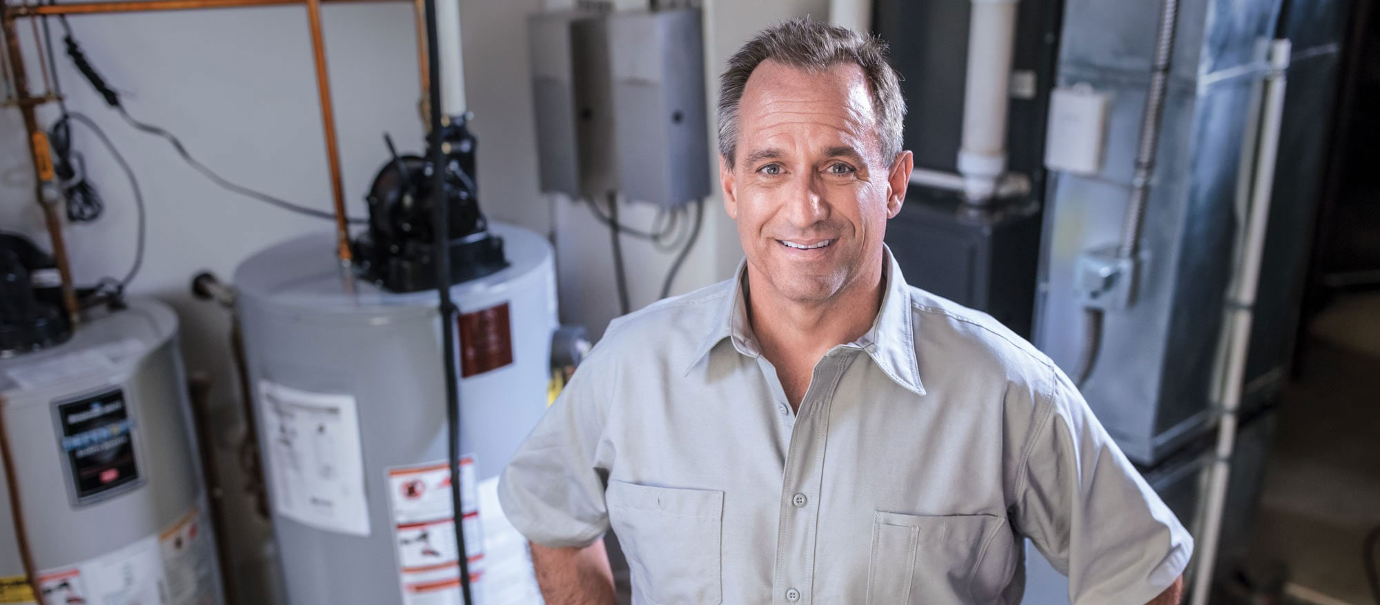 Un technicien partenaire de Supérieur Propane est debout devant un appareil de chauffage et un chauffe-eau.