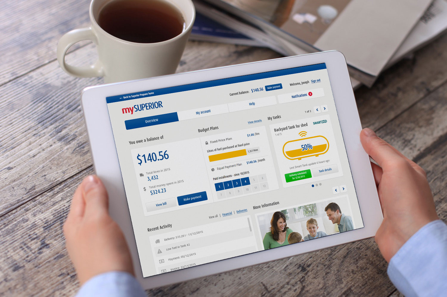 Personne assise à un bureau, tenant une tablette et regardant l'appli monSUPÉRIEUR en buvant un café