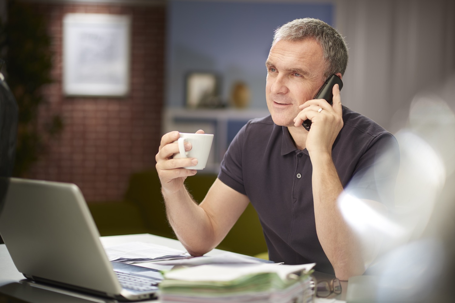 Homme assis devant un ordinateur, café à la main, parlant au téléphone des plans de tarification de Supérieur Propane.