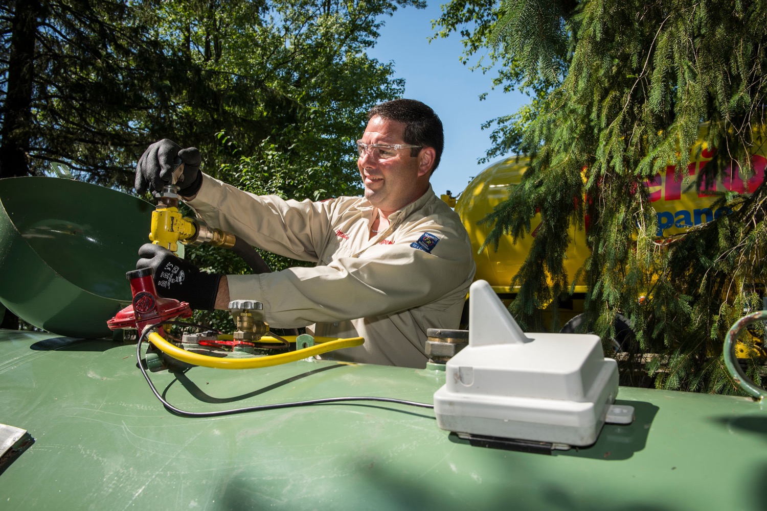 Employé de Supérieur Propane remplissant un réservoir de propane vert muni d'un capteur de réservoir intelligent.