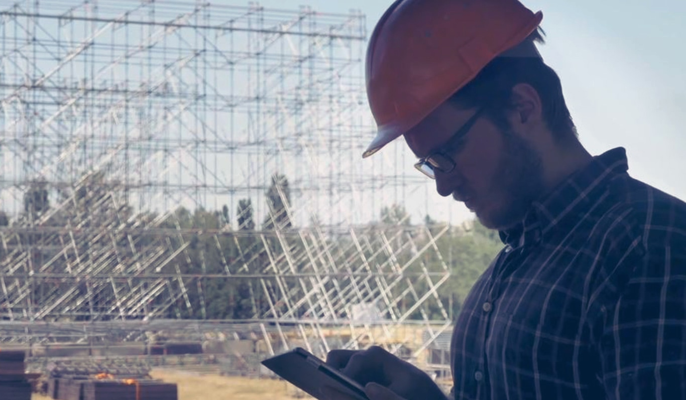 Un travailleur de la construction sur un chantier regarde une tablette.