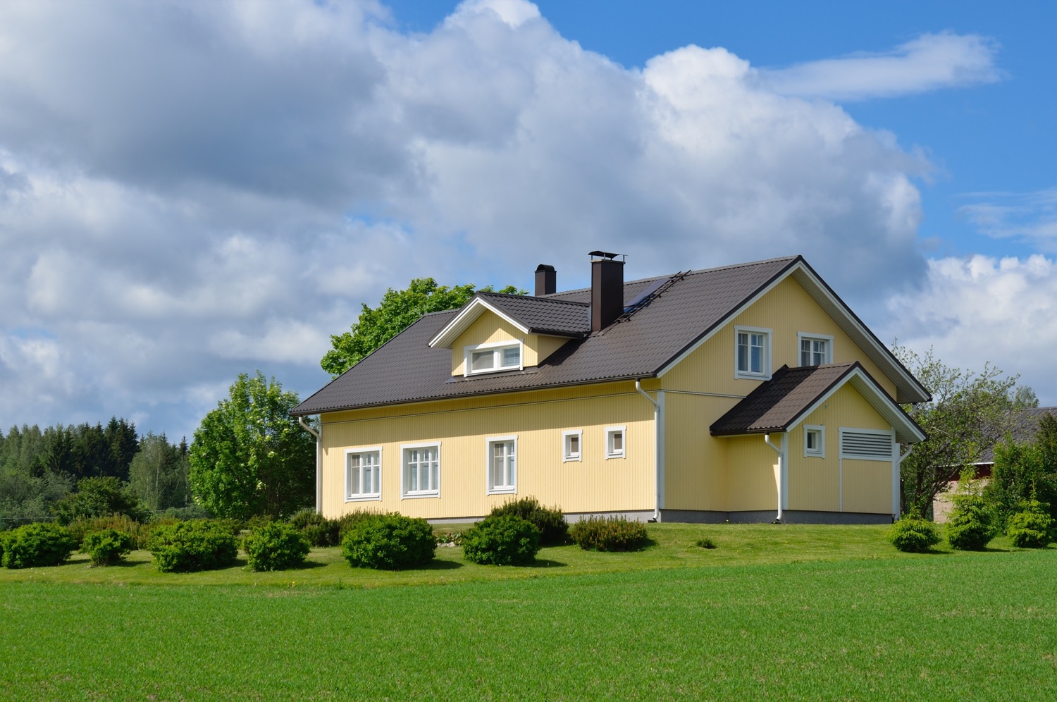 Une maison jaune dans un champ vert à la campagne