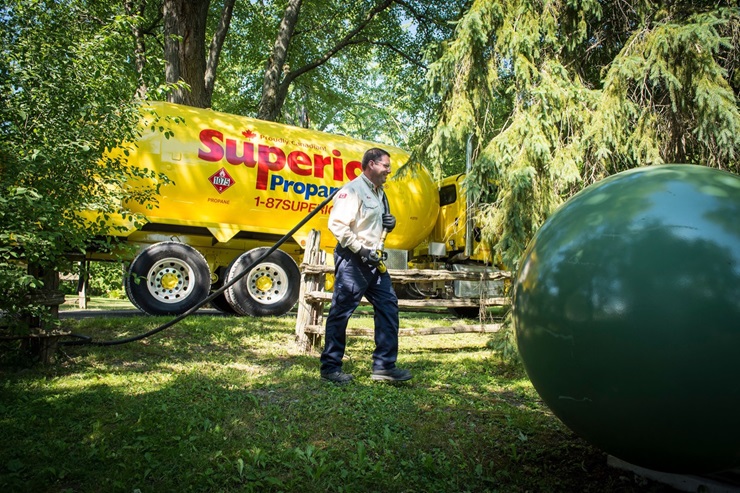 Un employé de Supérieur Propane transporte le tuyau de remplissage d’un camion-citerne à un réservoir de propane.