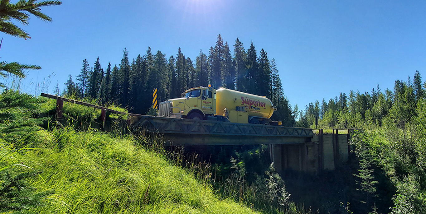 Un camion de Supérieur Propane sur un pont devant un paysage pittoresque.