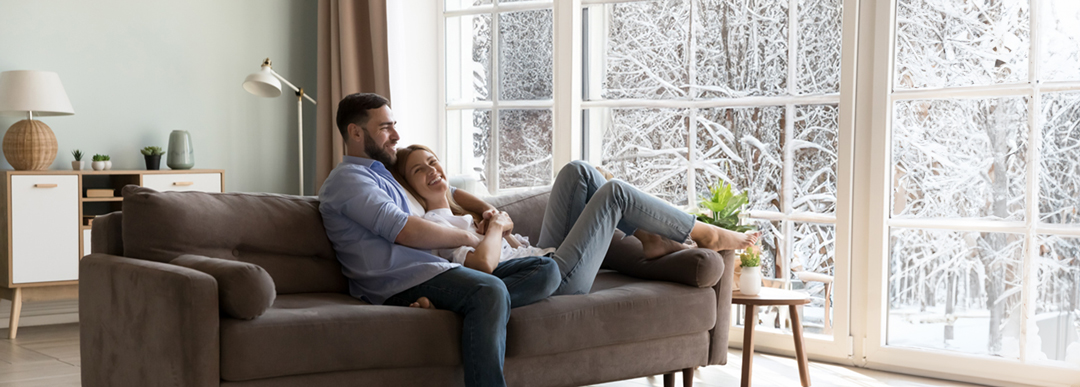 homme et femme assis dans le salon regardant la neige à l'extérieur